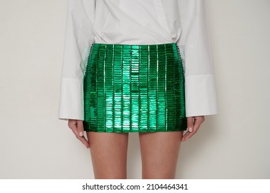 Girl in white shirt and green mini skirt in hand embroidered rectangular sequins. Caucasian slim woman. Horizontal photo with white background.