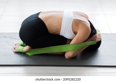 A Girl In A White Top And Black Cycling Shorts Posing In A Fetal Position Pulling On A Gymnastic Ribbon. Horizontal Photo