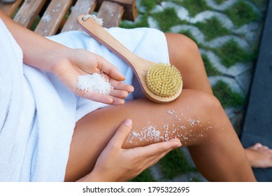 A Girl In A White Towel Sitting Makes A Foot Scrub With Sea Salt With A Brush From A Cactus Nap. Body Massage
