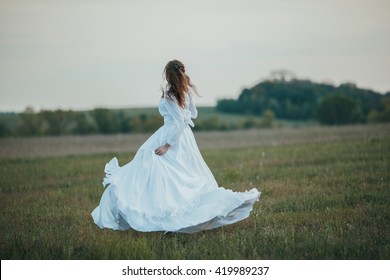 Girl In White Vintage Dress Walking Through The Spring Field.