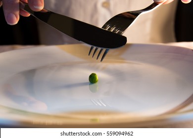A girl who is eating only one green pea on a plate.