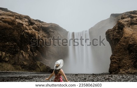 Girl who proudly standing with his arms raised in front of water wall of mighty waterfall.Women riding a swing.