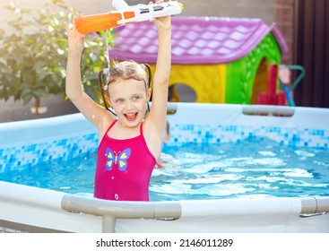 Girl Win The Game And Is Happy. Laughing Child Playing With Water Gun In Outdoor Swimming Pool On Summer Day. Pool Toys And Water Fun For Family With Children