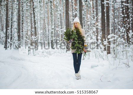 girl in winter forest holds branches in his hands
