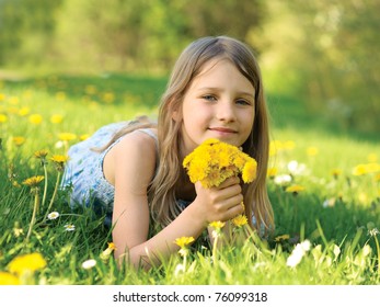 Girl wit a dandelions bouquet on green meadow