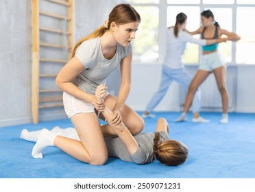 Girl and woman athletes practice self-defense wrestling. Training at Academy of Martial Arts martial arts hand-to-hand combat. - Powered by Shutterstock