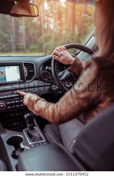 Girl woman in car interior leather jacket\
autumn and spring, in forest park, presses emergency stop button,\
switches on dimensions, accident on road, obstacle to cars signal\
about accident.