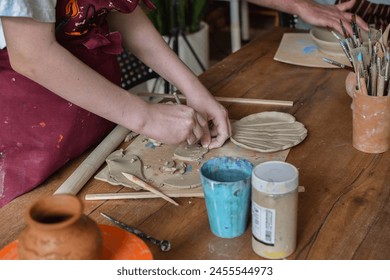 girl working with clay on the table in a pottery workshop - Powered by Shutterstock