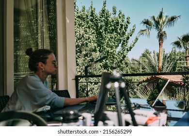 A girl working on the table on the terrace. Many laptops and other staff. Side view. High quality photo