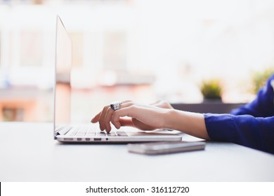 Girl Works At A Cafe On A Netbook Lying Close To The Phone, It Checks For New Mail And Surf The Internet