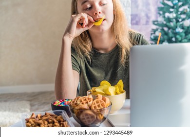 Girl Works At A Computer And Eats Fast Food. Unhealthy Food: Chips, Crackers, Candy, Waffles, Cola. Junk Food, Concept.