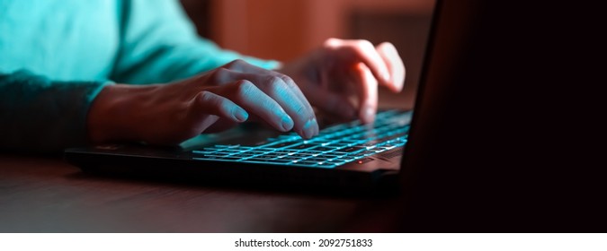 A girl works at a laptop at night online, texting, looking for information, studying, female hands on the keyboard close-up. - Shutterstock ID 2092751833