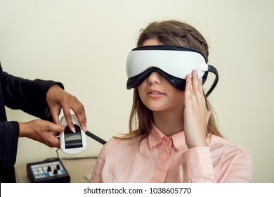 Girl is worried for her sight. Relaxed modern european woman sitting in office of eye care specialist waiting when procedure will be finished, wearing digital vision screener during check-up