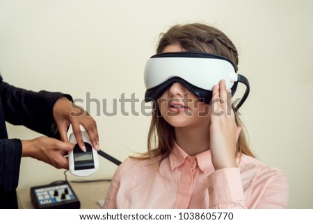 Girl is worried for her sight. Relaxed modern european woman sitting in office of eye care specialist waiting when procedure will be finished, wearing digital vision screener during check-up