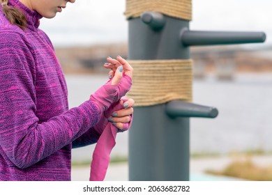 girl wrapping a wrist wrap around her hand before outdoor martial arts training against the traditional training dummy - Powered by Shutterstock