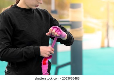 girl wrapping a wrist wrap around her hand before outdoor martial arts training against the traditional training dummy - Powered by Shutterstock