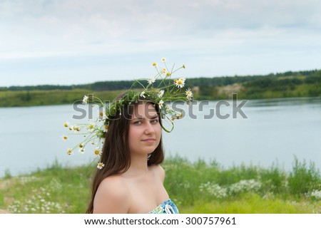 girl in a wreath of daisies on blue sky background