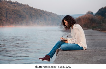 Girl writes diary by lake - Powered by Shutterstock