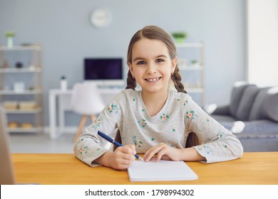 A Girl Writes In A Notebook The Text Of A School Lesson Sitting At A Desk At Home.