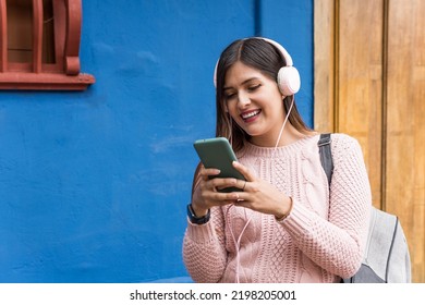 Girl Writing And Listening To Music On Cell Phone On Blue Background