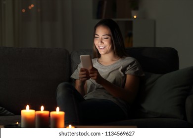 Girl Writing Messages On A Phone In The Night Sitting On A Couch In The Living Room At Home