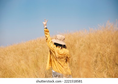 A Girl With A Yellow Jacket On The Way To The Smile, A Girl With A Yellow Jacket On The Way To Trek Or Hike. A Young Woman With A Straw Hat