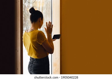 Girl in yellow jacket at the window calls someone on video link.