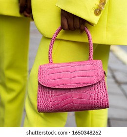 A girl in a yellow pantsuit with a small raspberry bag made of crocodile faux leather. Hit of the season, super cool thing for summer