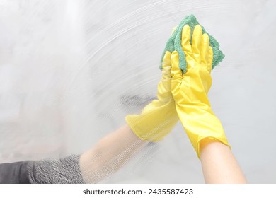 a girl in yellow rubber gloves cleans a mirror. Cleaning and polish mirror with rag and spray in bathroom. Housekeeping and cleaning service - Powered by Shutterstock