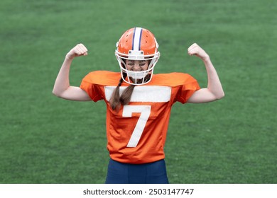 Girl or young woman with braids in helmet and uniform for American football players in dynamic motion showing strength or celebrating successful action on green grass background. - Powered by Shutterstock