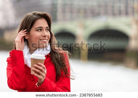 Girl or young woman drinking coffee in a disposable cup by Westminster Bridge in the background, London, England, Great Britain