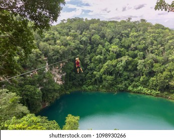 Girl Ziplining Over The Water Of A Cenote In The Mexican Jungle