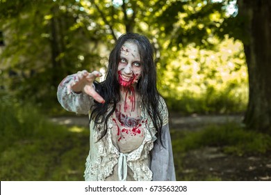 Girl zombie in the blood in the forest on the background of the house