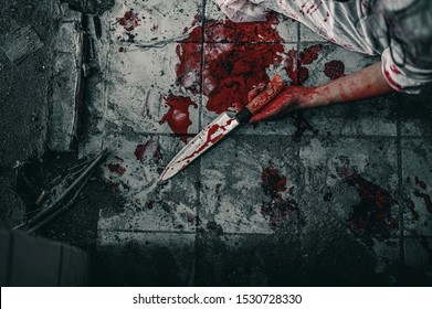 Girl zombie in the blood sitting hand holding knife smeared with blood with resentment  torture and ask for help in abandoned building. Halloween murder concept.