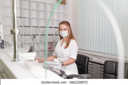 Girl-administrator In A White Coat And Mask Of A Medical Clinic.reception Of Patients.Admission To The Hospital