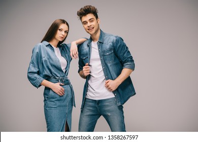 girlfriend in denim dress and smiling boyfriend in jeans and shirt looking at camera 