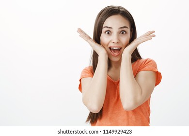 Girlfriend shows beautiful smile she made at dentist. Portrait of positive carefree woman with dark hair, holding spread palms near opened mouth and smiling broadly, being amazed and excited