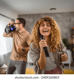 Girlfriend sing karaoke on mic with her boyfriend in the background - Powered by Shutterstock