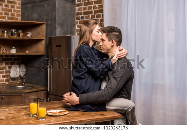 Girlfriend Sitting On Table Kitchen Kissing Stock Photo Edit Now