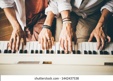 Girlfriend spend time in modern apartment. Girls learning piano playing. Top to bottom view crop hands making exercise on piano keyboard and watching tutors on smartphone screen.