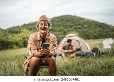 Girlfriend use mobile phone on camp with boyfriend in the background - Powered by Shutterstock