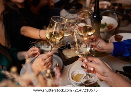 Girlfriends drinking wine and cheering while sitting in the bar. Selective focus on glasses.