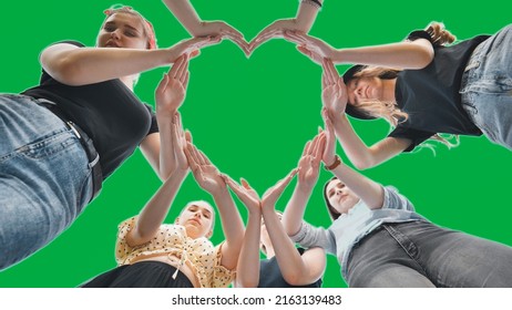 Girlfriends girls make a heart shape from their hands on a green background.