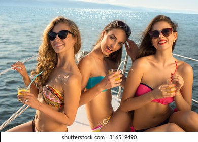 Girlfriends relaxing on a yacht. Girls at the sea. Cruise on a yacht. Girls smile. Glamour girl relaxing on a yacht.