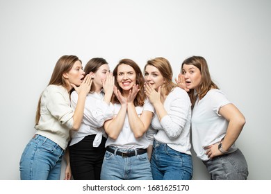 Girlfriends In Similar Clothes Tell Each Other Secrets On A White Background