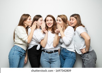 Girlfriends In Similar Clothes Tell Each Other Secrets On A White Background