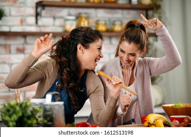 Girlfriends Singing In The Kitchen And Cooking. Woman Friends Having Fun At Home In The Kitchen.