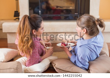 Girlfriends talking near a cup of coffee and cake.