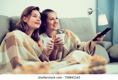 Girlfriends are watching TV and drfinking tea at home. - Powered by Shutterstock