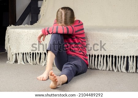 Girl's bare feet. Foot heel. Sad little girl sitting on the floor. European